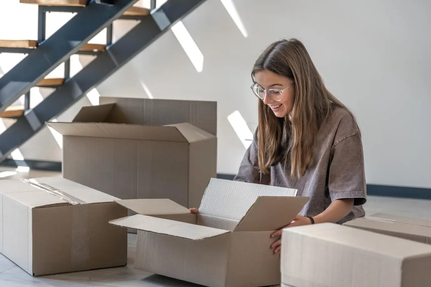 Mädchen mit Kartons beim Umzug und beim Auspacken einer Bestellung fürs neue Zuhause.